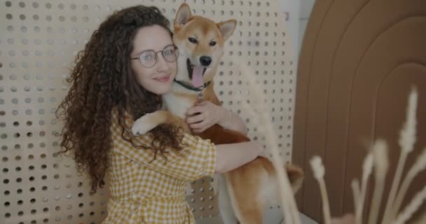 ペットフレンドリーなカフェでカメラを見て笑っている若い女性抱擁柴犬のスローモーションポートレート 動物と人々の概念 — ストック動画