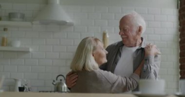 Mutlu yaşlı çiftin gülümseyerek dans etmesi evde romantik bir ilişki yaşaması. İlişki ve eğlence zamanı kavramı.