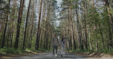 Kız ve erkek mutlu genç çift güzel bir yaz gününde ormanda el ele tutuşup sohbet ediyorlar. İlişki ve eğlence etkinliği kavramı.