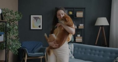Evcil köpekle dans eden neşeli kız evde kulaklıkla müzik dinleyerek eğleniyor. Boş zaman ve eğlence konsepti.