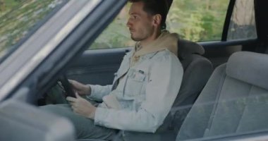 Genç adamın emniyet kemerini bağlarken ve kırsalda araba sürmeye hazırlanırken yan görüntüsü. Otomobil ve ulaşım kavramı.