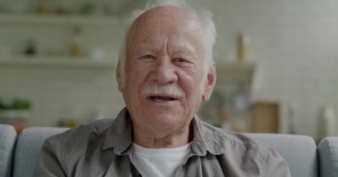 Konuşan, el sallayan ve kameraya bakan yaşlı bir adamın portresi evde çevrimiçi video görüşmesi yapıyor. İletişim ve kıdemli kişi kavramı.