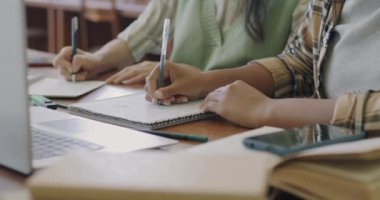 Kampüste öğrenciler öğrenirken masadaki dizüstü bilgisayarlarla not defterlerini karıştıran kadınların yakın çekimi. Kişisel eğitim ve bilgi kavramı.