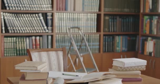 Kütüphanede Rafları Kitaplıkları Olan Kitaplarla Dolu Bir Masa Arka Planda — Stok video