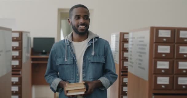 Dolly Shot Carefree African American Man Holding Books Walking Library — Stock Video