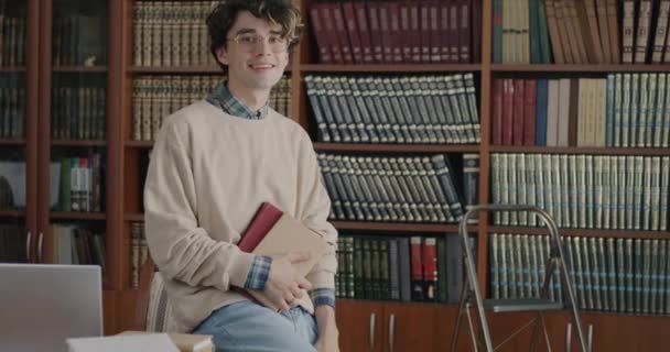 Kitapları Tutan Üniversite Kütüphanesinde Gülümseyen Zeki Genç Bir Öğrencinin Yavaş — Stok video