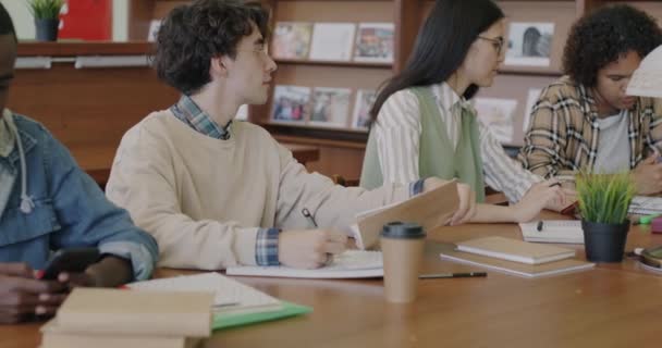 Wielorasowa Grupa Młodych Ludzi Uczących Się Bibliotece Odrabiających Lekcje Pomocą — Wideo stockowe