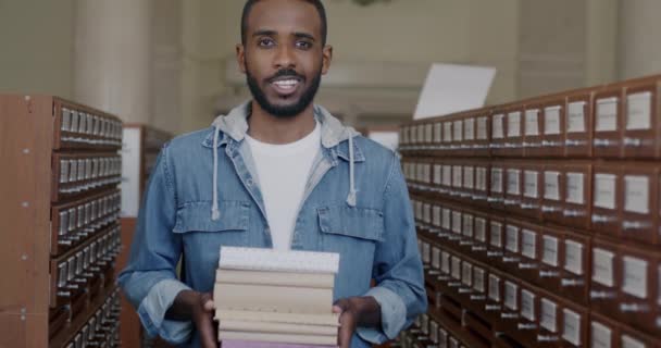 Alegre Estudiante Afroamericano Sosteniendo Libros Pie Biblioteca Sonriendo Mirando Cámara — Vídeos de Stock