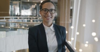 Orta Doğulu başarılı bir iş kadınının portresi gülümseyerek güzel bir otel lobisinde duruyor ve mutlu bir yüzle kameraya bakıyor..