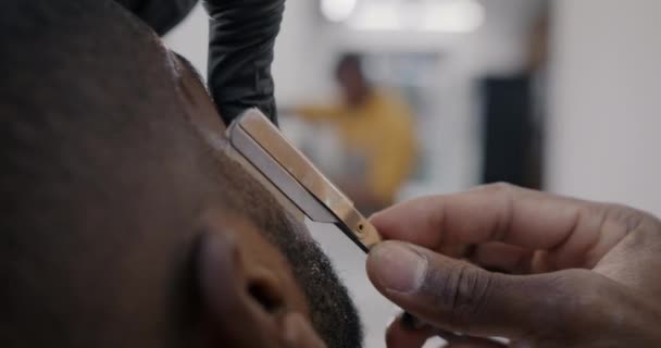 在理发店里 理发师在照顾顾客时 用锋利的刀片在男性脸上刮胡子 进行密切合作 美容美发概念 — 图库视频影像