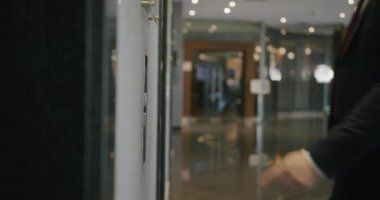 Otel lobisindeki asansör düğmesine adam asansörü beklerken, iş adamlarının yakın çekimleri. İç ve insan konsepti.