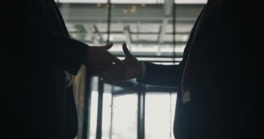 İş adamları otellerde iletişimdeyken, erkek ellerinin cam kapılara karşı titremesi ve el kol hareketi yapması yavaş çekimde.