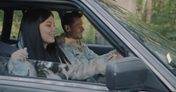 田舎を運転しながら音楽を聴きながら踊る若い女性の車の乗客 カップルのコンセプトのためのロードトリップと楽しい休暇 — ストック動画