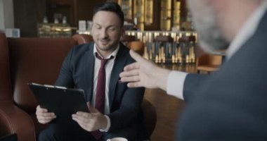 İki iş adamının kahve fincanlarını cızırdatan ve otel lobisinde el sıkışan belgeyi okurken çekilen omuz üstünden. Halk ve işbirliği kavramı.