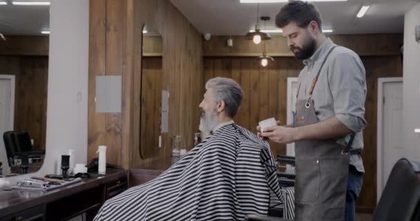 专业理发师打开酒瓶 并在理发店为客户提供美容产品 人与美容院概念 — 图库视频影像
