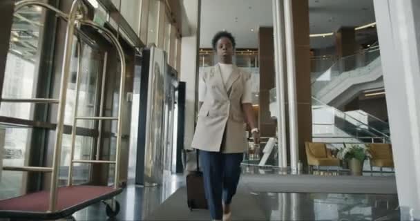 Долли Сняла Серьезного Афро Американского Предпринимателя Гуляющего Гостиничному Коридору Чемоданом — стоковое видео