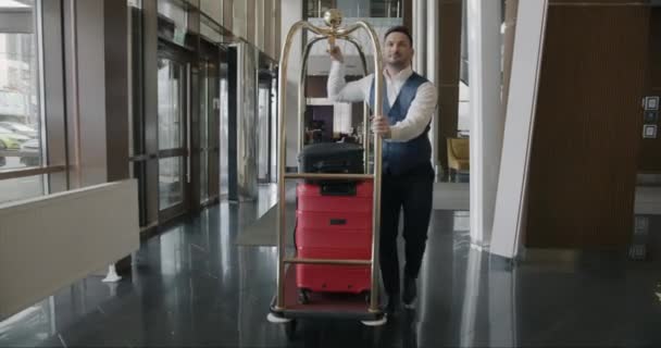 Hotelowy Goniec Mundurze Idzie Korytarzem Pchając Wózek Bagażem Pracującym Sam — Wideo stockowe