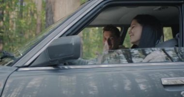 Mutlu genç çift yol dansına başlıyor. Arka planda yeşil ormanlarla birlikte arabada oturarak şarkı söylüyorlar. Gençlik ve ulaşım kavramı.