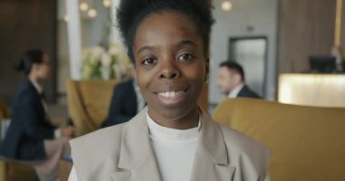 Modern otel lobisinde gülümseyen ve kameraya bakan Afro-Amerikan iş kadını portresi. Pozitif duygular ve insanlar kavramı.