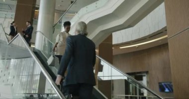 Afrikalı Amerikalı iş kadını modern otel lobisinde merdivenlerden iniyor. Şık giyinmiş, takım elbiseli insanlarla tanışıyor.