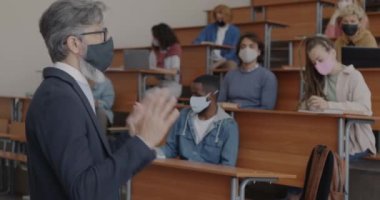 Üniversite profesörü, kovid 19 enfeksiyonunu önlemek için tıbbi maske takan öğrencilere konuşuyor. Salgın ve eğitim kavramı.