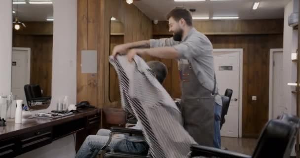 理发师在现代时尚理发店与男性顾客一起工作 而成熟的男性顾客则坐在镜子前的椅子上 风格和人的概念 — 图库视频影像