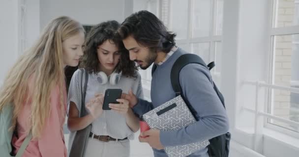 快乐的男人和女人用智能手机聊天 然后在大学走廊和朋友打招呼 人与现代生活方式概念 — 图库视频影像
