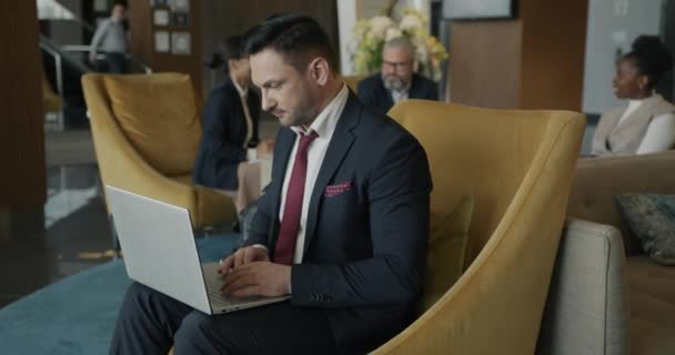 西装革履的商人正在商务旅行期间用笔记本电脑打字 集中在宾馆休息室的互联网活动上 现代技术和旅行概念 — 图库视频影像