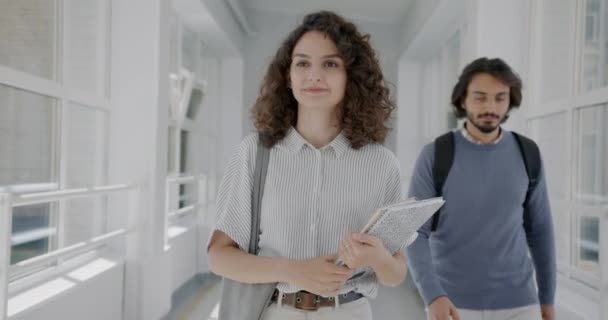 本を運ぶ人を手挨拶手を振って 高校の廊下を歩いて優しい若い女性学生のスローモーションの肖像画 若者と近代的な教育の概念 — ストック動画