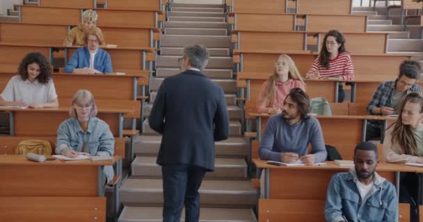Universitetsprofessor Föreläser För Multietnisk Grupp Studenter Som Talar Gestikulerande Promenader — Stockvideo