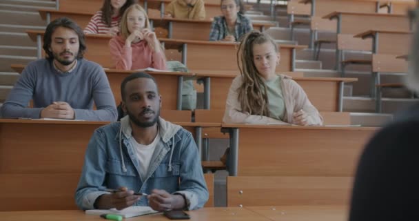 兴高采烈的非洲裔美国人和其他学生坐在大学堂里和老师问话 专业讨论和教育概念 — 图库视频影像