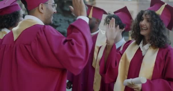Grupo Estudantes Vestidos Formatura Chapéus Fazendo Alto Cinco Gesto Segurando — Vídeo de Stock