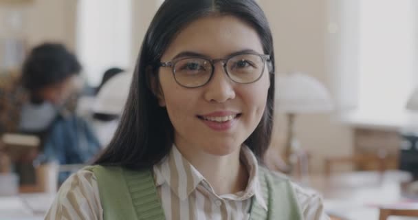 在高中图书馆里 聪明的亚洲女学生面带微笑地看着相机的肖像 积极情绪与现代教育理念 — 图库视频影像