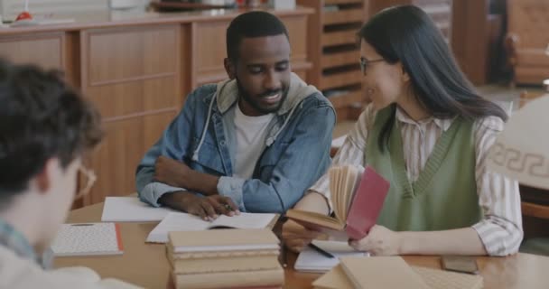 Африканський Американець Азіатка Навчаються Разом Читати Книгу Столом Класі Коледжу — стокове відео