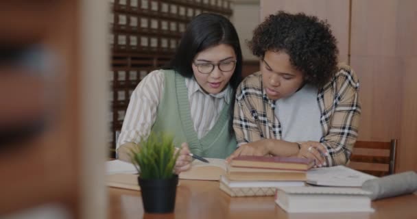 Jovens Mulheres Afro Americanas Asiáticas Estudando Juntas Biblioteca Discutindo Livro — Vídeo de Stock