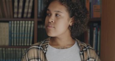 Mutlu Afro-Amerikan kadın portresi kitapçıda durup kameraya bakarak memnuniyetini ifade ediyor. Edebiyat ve kitapçı konsepti.