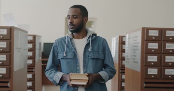 Hombre Afroamericano Alegre Con Libros Las Manos Caminando Sala Biblioteca — Vídeos de Stock