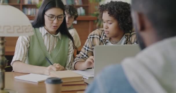 아시아 아프리카 미국인젊은 여성들 도서관에서 프로젝트를 하면서 노트북에 이야기하고 사용하고 — 비디오