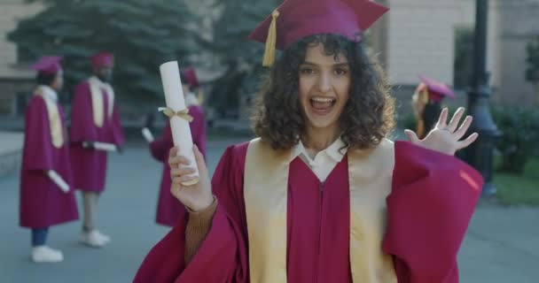 在学校毕业典礼上 快乐的年轻女性微笑着 尖叫着 表达着幸福 并获得了毕业文凭 教育和成功概念 — 图库视频影像