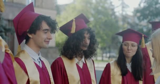 在大学里 各色人等的学生与女教授握手 享受着毕业典礼 身穿长袍 头戴帽子的年轻人 — 图库视频影像