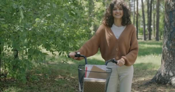 拿着自行车站在公园里的年轻女学生慢镜头 微笑着看着镜头 交通和积极生活方式概念 — 图库视频影像