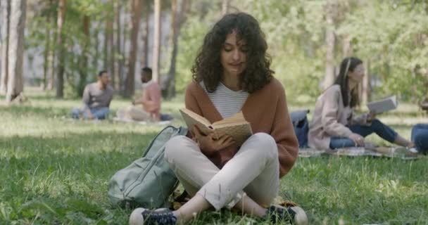 Retrato Jovem Despreocupada Lendo Livro Interessante Sorrindo Sentado Gramado Parque — Vídeo de Stock