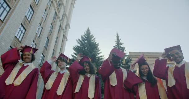 Neşeli Erkek Kadınlar Elbise Giyip Gökyüzüne Şapka Fırlatarak Üniversite Kampüsünde — Stok video