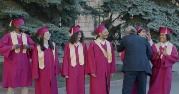 Decano Universidad Felicitando Grupo Estudiantes Trajes Graduación Sombreros Abrazando Los — Vídeos de Stock