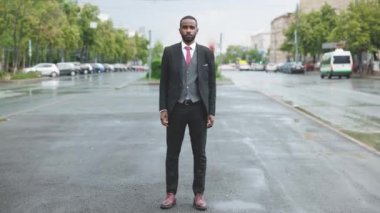 Arabalar hareket halindeyken sokakta tek başına duran ciddi bir Afro-Amerikalı 'nın hızlandırılmış portresi. Toplum ve şehir yaşam tarzı kavramı.