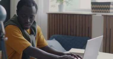 Young student African American man working with laptop computer typing busy with college assignment from home. Education and modern technology concept.