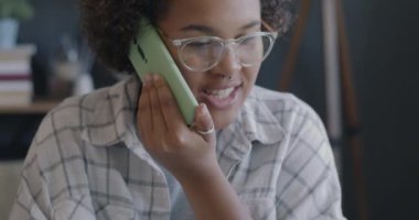 Female employee speaking on mobile phone and working with laptop computer in office. Business communication and job activity concept.