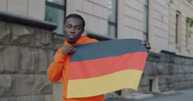 Slow motion portrait of carefree African American man dancing with German national flag smiling looking at camera. People and countries concept.
