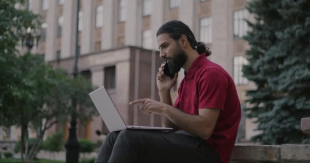 Mellanösterns Man Talar Mobiltelefon Och Arbetar Med Bärbar Dator Utanför — Stockvideo