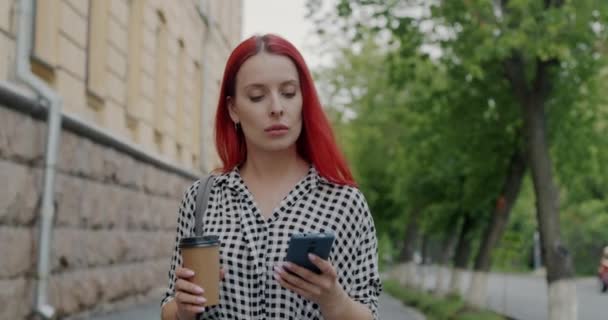 无忧无虑的学生拿着咖啡杯和智能手机在城市里走来走去 动作缓慢 在线通信和社交媒体概念 — 图库视频影像